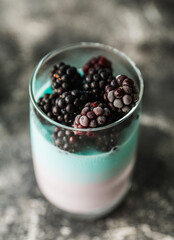Dessert with yogurt and blackberry in glass on the dark rustic background. Selective focus. Shallow depth of field.