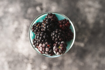 Dessert with yogurt and blackberry in glass on the dark rustic background. Selective focus. Shallow depth of field.