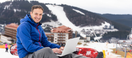 snowboarder typing on the laptop in the mountains winter