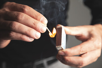 a man sets fire to a wooden match