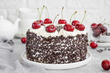 Black forest cake, Schwarzwald pie. Cake with dark chocolate, whipped cream and cherry on a gray concrete background. Copy space.