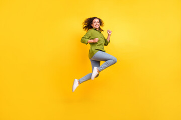 Fototapeta na wymiar Photo of beautiful funky funny positive stylish woman dressed green shirt jumping high running smiling isolated yellow color background