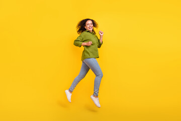 Fototapeta na wymiar Photo of positive beautiful funky funny energetic woman dressed green shirt jumping high running smiling isolated yellow color background