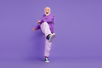 Fototapeta na wymiar Full length body size view of nice cool cheerful grey-haired man moving having fun isolated over bright violet purple color background
