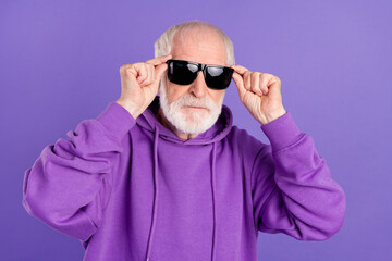 Portrait of attractive content serious grey-haired man touching specs modern look isolated over bright violet purple color background