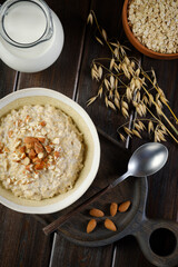 Oatmeal porridge with almonds, milk and some ears of oats closeup. Healthy eating. Vegan and vegetarian food. Flat lay composition.