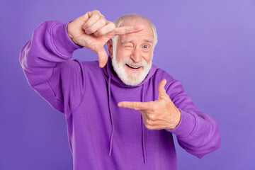 Portrait of attractive cheerful gray-haired man showing frame shop snap isolated over bright violet purple color background