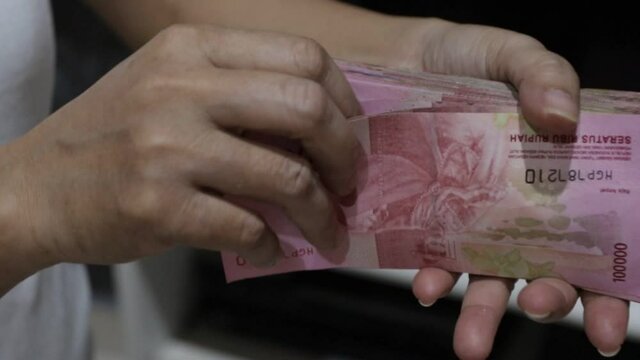hand counting Indonesian rupiah banknotes in the 100 thousand rupiah denomination