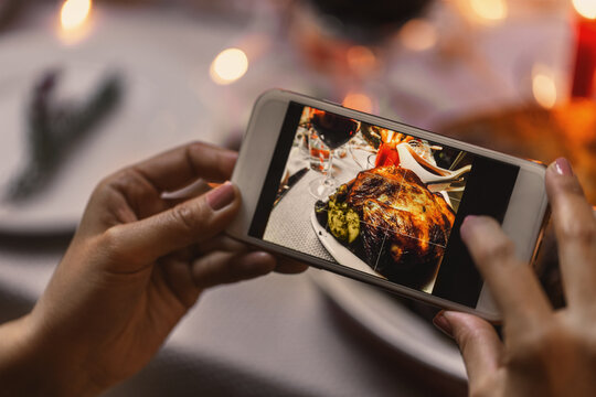 holidays, technology and celebration concept - hands with smartphone photographing food at christmas dinner