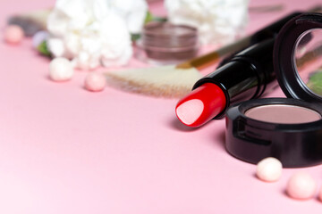 Obraz na płótnie Canvas Concept spring make up. Decorative cosmetics and carnation flower on pink background.