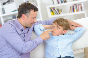 Man pressing nose of young child