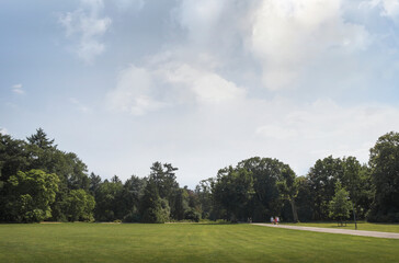 Landscape park, summer, grass meadow. People walk along the path