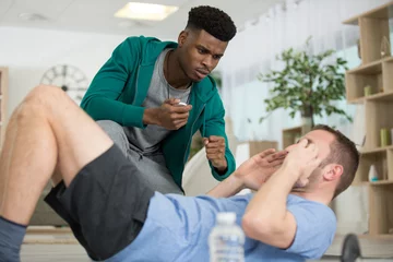 Deurstickers personal trainer encouraging mature man doing sit-ups © auremar