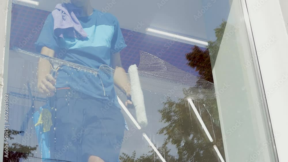 Wall mural a professional cleaning service worker washes the windows with special foam and cleans them.