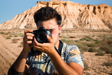 Young man with a camera in Bardenas Reales desert, Navarra, Basque Country.