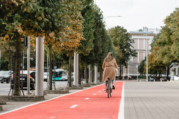 traffic, city transport and people concept - woman riding bicycle along red bike lane or two way...