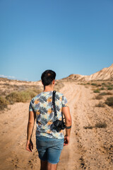 Naklejka premium Young man with a camera in Bardenas Reales desert, Navarra, Basque Country.