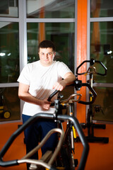 Athletic young man having stationary bike workout