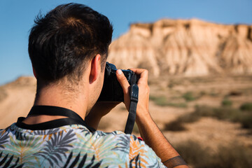 Young man with a camera in Bardenas Reales desert, Navarra, Basque Country.