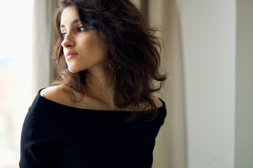 pretty brunette near the window in black dress posing luxury model