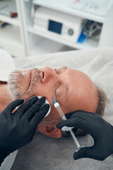 Obraz na płótnie Canvas Man having anti-aging injection procedure in cosmetology clinic