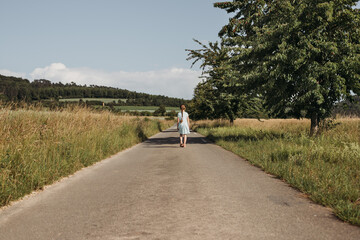 the girl is walking alone along the road. Rest from the hustle and bustle, loneliness, freedom. The...