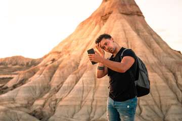 Young caucasian man using a smartphone while visiting Bardenas Reales desert in Navarra, Basque Country.