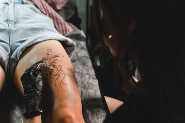Woman tattoo artist doing tattoo in studio, making tattoo on body. closeup
