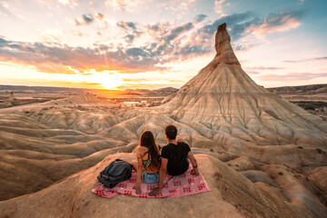 One young man and one young woman watching the sunset at Castildetierra in Bardenas Reales desert, Navarra, Basque Country. - obrazy, fototapety, plakaty