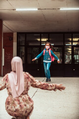 Fototapeta premium Schoolgirl runs into her mothers arms after school.New normal. Education during the Covid-19 pandemic. Selective focus.