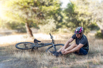 Male cyclist in an accident in the countryside. A young cyclist lying on the ground after suffering...