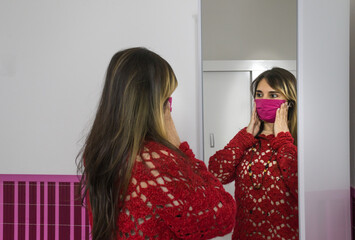 Joven mujer morena feliz delante del espejo con máscara
Probarse o elegir ropa de abrigo con...