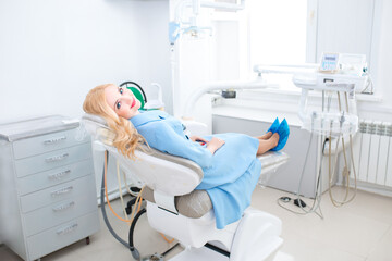 Dental clinic. A beautiful young girl with a snow-white smile is sitting in the dental chair at the reception at the dentist. Dentistry and orthodontist. Dental treatment and bite correction.Toothache