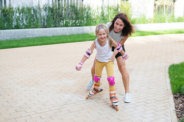 Caucasian woman teaches her daughter to skate on roller skates.