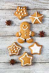 Christmas gingerbreads in the shape of a star and man with patterns of glaze and spices on a white wooden background.