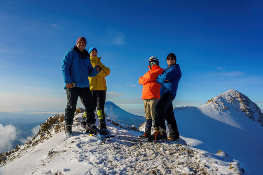 group of hikers, tourists or friends stands on top of the mountain taking a photo
