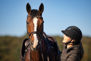 Fototapeta premium Horse saddled in head portrait from the front, the rider looks at her horse with a laugh..