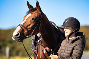 Obraz premium Horse saddled in head portrait from the front, horse looks attentively to the right with raised upper lip and the rider laughs and holds it by the reins..