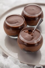 chocolate dessert with a spoon in a glass container on a white background