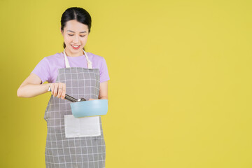 Young Asian housewife posing on yellow background