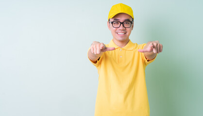 Young Asian delivery man posing on green background