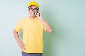 Young Asian delivery man posing on green background