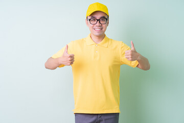 Young Asian delivery man posing on green background