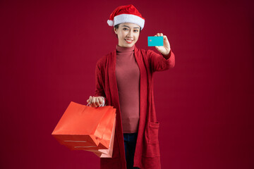 Young Asian woman wearing christmas hat on red background