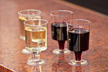 Plastic glasses with wine close up. Different types of wine on a marble table.