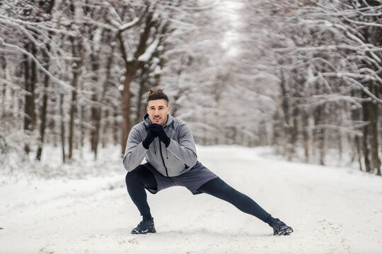 Fit Sportsman Doing Stretching And Warmup Exercises In Forest At Snowy Winter Day. Healthy Life, Warmup, Cold Weather