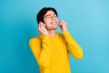 Photo portrait man listening to music in earphones isolated pastel blue color background