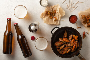Fresh beer with fried shrimps on a light table, top view