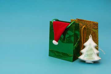 Two packages with gifts, a Christmas tree and a Santa Claus hat on a blue background. Holiday gifts shopping concept
