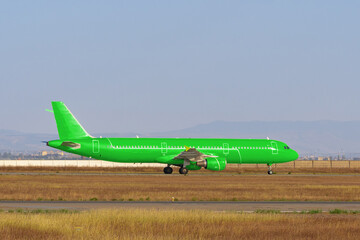 Green passenger airplane at the airport on sunny day